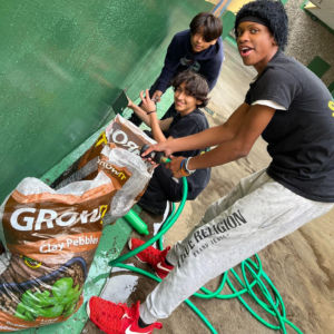 students pouring clay pebbles into a grow bed